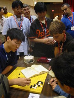 Three Japanese professional Go players observe some younger amateurs as they dissect a life and death problem in the corner of the board, at the US Go Congress in Houston, 2003.